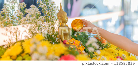 Happy Songkran festival day in Thailand or Thai Happy New Year. hand pouring water on golden Buddha statue with flowers and garland in. Holiday and culture concept Happy Songkran festival day in Thailand or Thai Happy New Year. hand pouring water on golden Buddha statue with flowers and garland in. Holiday and culture concept 138585839