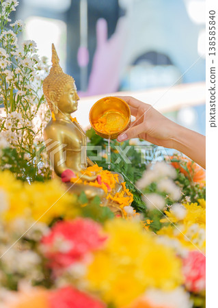 Happy Songkran festival day in Thailand or Thai Happy New Year. hand pouring water on golden Buddha statue with flowers and garland in. Holiday and culture concept Happy Songkran festival day in Thailand or Thai Happy New Year. hand pouring water on golden Buddha statue with flowers and garland in. Holiday and culture concept 138585840