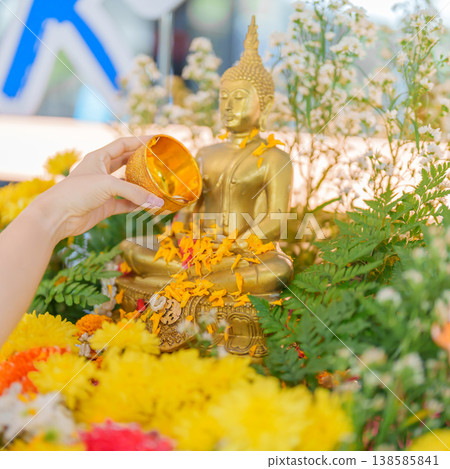 Happy Songkran festival day in Thailand or Thai Happy New Year. hand pouring water on golden Buddha statue with flowers and garland in. Holiday and culture concept Happy Songkran festival day in Thailand or Thai Happy New Year. hand pouring water on golden Buddha statue with flowers and garland in. Holiday and culture concept 138585841