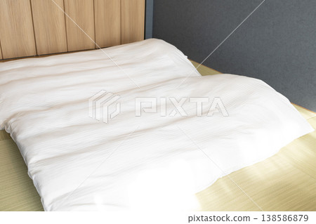 一張潔白的日式床墊和一塊木紋床頭板擺放在日式房間的榻榻米上。 一張潔白的日式床墊和一塊木紋床頭板擺放在日式房間的榻榻米上。 138586879