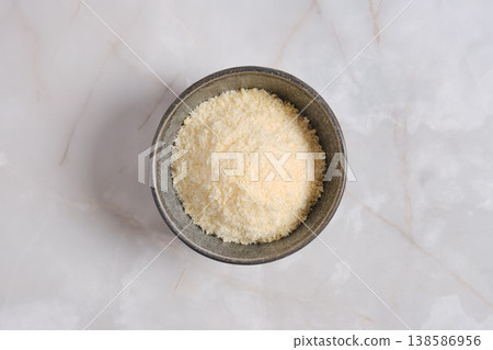 Grated cheese in a bowl on a marble surface in a kitchen setting 138586956