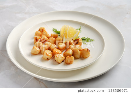 Scallops served with lemon and herbs on a white plate in a restaurant setting Scallops served with lemon and herbs on a white plate in a restaurant setting 138586971