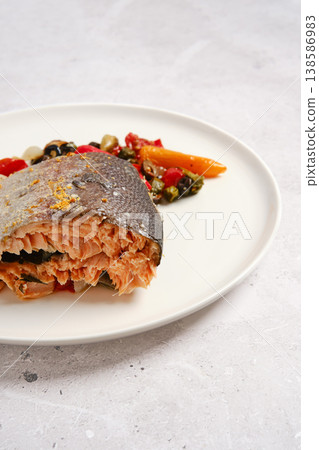 Salmon dish served with vegetables on a white plate in a simple kitchen setting Salmon dish served with vegetables on a white plate in a simple kitchen setting 138586983