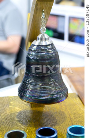 Object printing on 3D printer from melting metal thread. Model bell printed on 3D printer from filament of molten metal. New 3D printing modeling manufacturing technology. Additive progressive Object printing on 3D printer from melting metal thread. Model bell printed on 3D printer from filament of molten metal. New 3D printing modeling manufacturing technology. Additive progressive 138587149