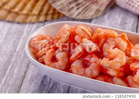 Cooked peeled shrimp in a ceramic bowl on a rustic gray wooden table with a seashell. Cooked peeled shrimp in a ceramic bowl on a rustic gray wooden table with a seashell. 138587450