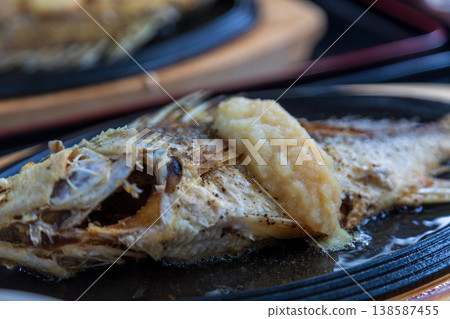 Delicious grilled fish served on a hot plate with rich garlic sauce at Awase Fishing Port in Okinawa, Japan. Delicious grilled fish served on a hot plate with rich garlic sauce at Awase Fishing Port in Okinawa, Japan. 138587455