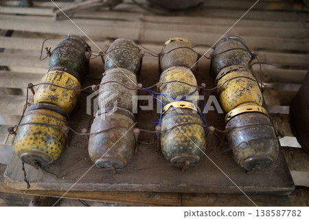 A collection of vintage M59 fragmentation grenades, likely from the Vietnam War era, displayed on a wooden surface 138587782