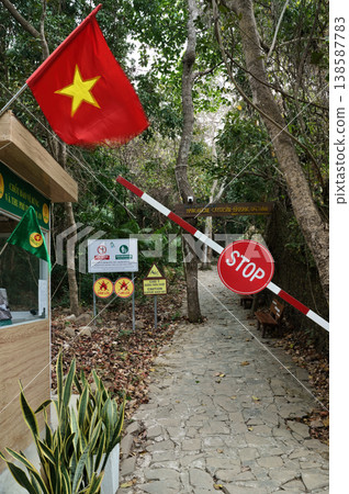 A red and yellow Vietnamese flag flies proudly at the entrance to a natural park, with a stop barrier and signs indicating rules A red and yellow Vietnamese flag flies proudly at the entrance to a natural park, with a stop barrier and signs indicating rules 138587783
