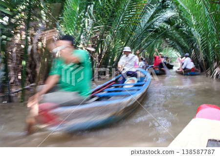 Tourists navigate narrow canals under lush palm trees in the Mekong Delta, Vietnam, experiencing local life and transportation 138587787