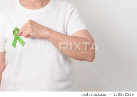 Elderly with light Green Ribbon for concept of May Celiac Awareness month, Lyme disease, September Lymphoma, Mental Health Awareness month and October Liver cancer. Health and world cancer day Elderly with light Green Ribbon for concept of May Celiac Awareness month, Lyme disease, September Lymphoma, Mental Health Awareness month and October Liver cancer. Health and world cancer day 138588599