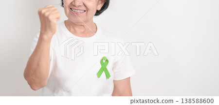 Elderly with light Green Ribbon for concept of May Celiac Awareness month, Lyme disease, September Lymphoma, Mental Health Awareness month and October Liver cancer. Health and world cancer day Elderly with light Green Ribbon for concept of May Celiac Awareness month, Lyme disease, September Lymphoma, Mental Health Awareness month and October Liver cancer. Health and world cancer day 138588600