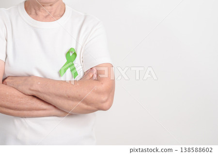 Elderly with light Green Ribbon for concept of May Celiac Awareness month, Lyme disease, September Lymphoma, Mental Health Awareness month and October Liver cancer. Health and world cancer day Elderly with light Green Ribbon for concept of May Celiac Awareness month, Lyme disease, September Lymphoma, Mental Health Awareness month and October Liver cancer. Health and world cancer day 138588602