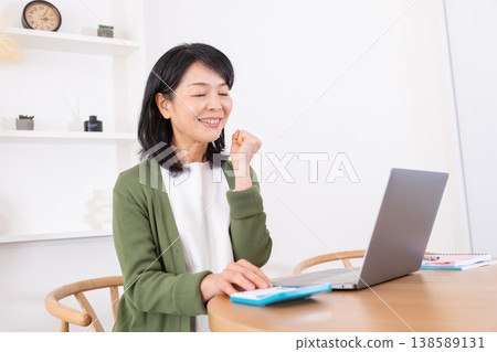 一位五十多歲的家庭主婦在做計算時做出了一個得意的手勢。 一位五十多歲的家庭主婦在做計算時做出了一個得意的手勢。 138589131