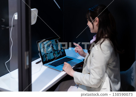 A female office worker gives a presentation via video conference using a private pod. 138590073