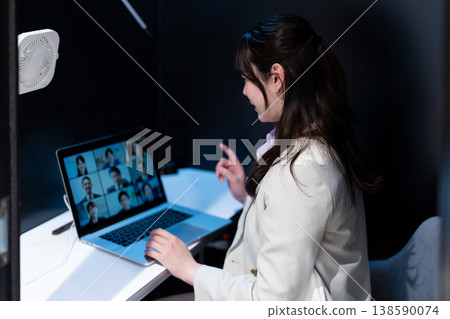 A female office worker gives a presentation via video conference using a private pod. A female office worker gives a presentation via video conference using a private pod. 138590074