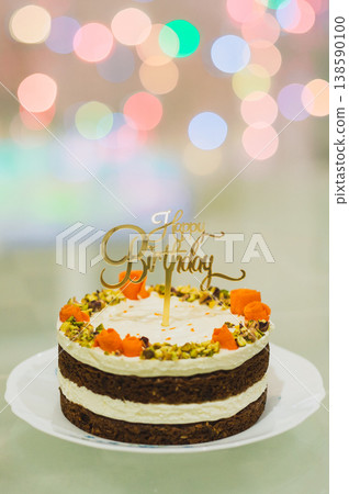 Birthday cake with Happy Birthday topper against a colorful bokeh background. Birthday cake with Happy Birthday topper against a colorful bokeh background. 138590100