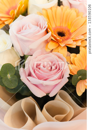 Elegant pastel bouquet of pink roses and orange gerbera with soft wrapping in vertical. Elegant pastel bouquet of pink roses and orange gerbera with soft wrapping in vertical. 138590106