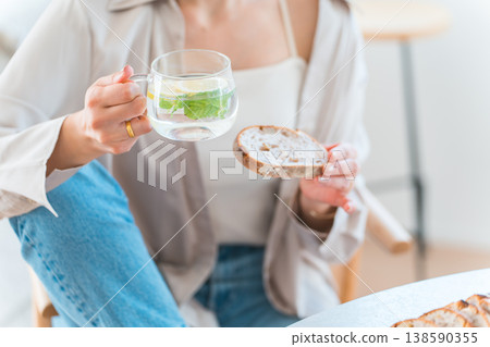 Young Asian woman having breakfast at the dining table Young Asian woman having breakfast at the dining table 138590355