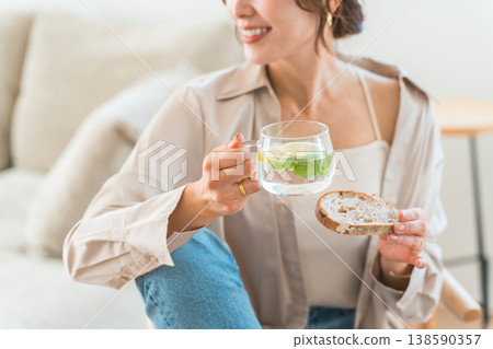 一位年輕的亞洲女性正在餐桌旁吃早餐。 138590357