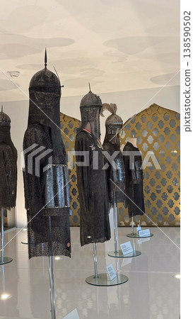 Collection of medieval chainmail armor with helmets displayed on mannequins in Malbork Castle museum Poland. Historical armor, protection and exhibition concept Collection of medieval chainmail armor with helmets displayed on mannequins in Malbork Castle museum Poland. Historical armor, protection and exhibition concept 138590502