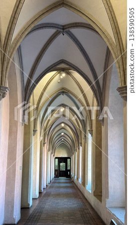 Long gothic corridor inside Malbork Castle in Poland with pointed arches columns and tiled floor leading to doorway. Architecture, history and heritage concept Long gothic corridor inside Malbork Castle in Poland with pointed arches columns and tiled floor leading to doorway. Architecture, history and heritage concept 138590505