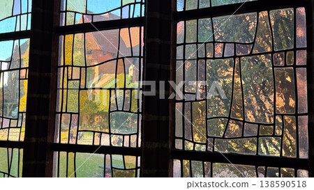 Ancient stained glass windows inside Malbork Castle in Poland with abstract geometric patterns and exterior view through colored panes. Architecture, history and heritage concept Ancient stained glass windows inside Malbork Castle in Poland with abstract geometric patterns and exterior view through colored panes. Architecture, history and heritage concept 138590518