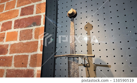 Medieval sword with corroded blade and simple guard displayed on museum wall inside Malbork Castle in Poland. Weapon, history and museum concept Medieval sword with corroded blade and simple guard displayed on museum wall inside Malbork Castle in Poland. Weapon, history and museum concept 138590519