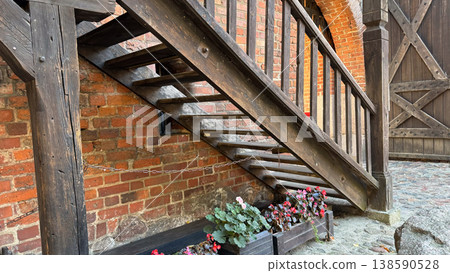 Wooden stairs and railing with flower boxes against red brick wall at Malbork Castle in Poland courtyard. Architecture, detail and historical design concept 138590528