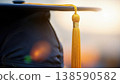 Close up of black graduation cap with gold tassel in warm sunset bokeh lights symbolizing academic success, achievement and completion. 138590582