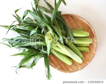 Young corn with the husks on, placed on a bamboo sieve Young corn with the husks on, placed on a bamboo sieve 138590643