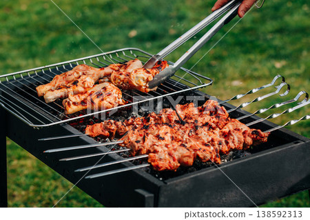 Pork skewers and chicken feet marinated grilling on rack over coals, spring barbecue in backyard Pork skewers and chicken feet marinated grilling on rack over coals, spring barbecue in backyard 138592313