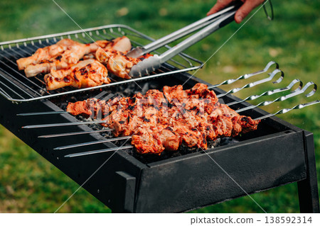 Pork skewers and chicken feet marinated grilling on rack over coals, spring barbecue in backyard Pork skewers and chicken feet marinated grilling on rack over coals, spring barbecue in backyard 138592314