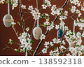 Decorative Easter eggs hanging on a string from a flowering cherry blossom branch indoors 138592318