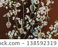 Decorative Easter eggs hanging on a string from a flowering cherry blossom branch indoors 138592319