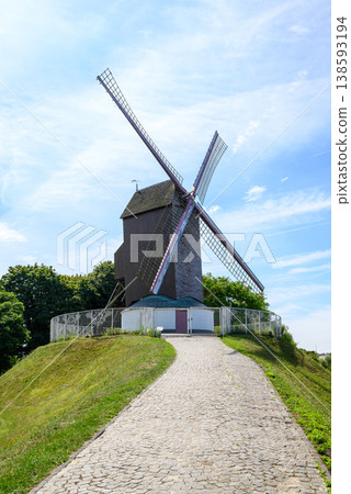 Traditional windmill on grassy hill with cobblestone path Traditional windmill on grassy hill with cobblestone path 138593194