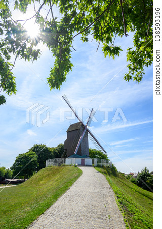 Wooden windmill on grassy hill under blue sky Wooden windmill on grassy hill under blue sky 138593196