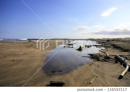 The sandy beach and tide pools along the coast as the tide gradually recedes after reaching its peak at high tide. 138593517
