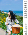 一位年輕女子騎著自行車穿過沿海的花田。 138593632