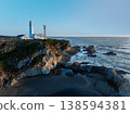日出時的燈塔和拍打著海岸的白色浪花。 138594381