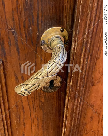 Ornate brass door handle on antique wooden door with visible keyhole, suitable for background Ornate brass door handle on antique wooden door with visible keyhole, suitable for background 138594776