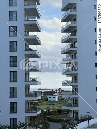 High-rise residential buildings with balconies and view of distant houses, sky, and clouds 138594780