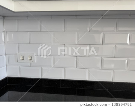 White subway tile kitchen backsplash with black countertop, electrical outlets visible, background White subway tile kitchen backsplash with black countertop, electrical outlets visible, background 138594791