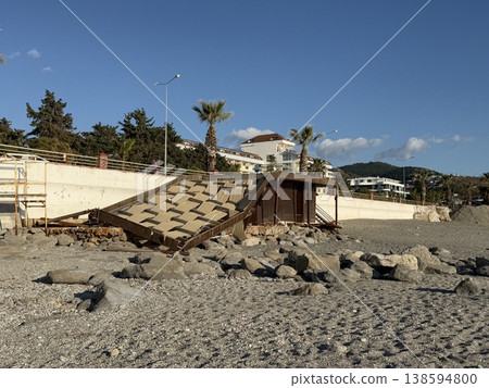 Beach scene with weathered wooden structure and rocky coastline under clear blue sky background Beach scene with weathered wooden structure and rocky coastline under clear blue sky background 138594800