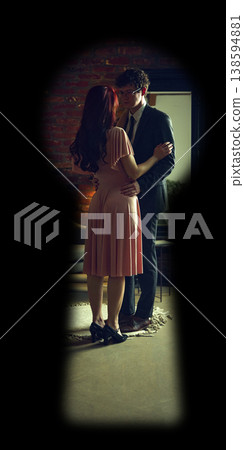 Couple embracing in intimate moment in bedroom seen through keyhole. Couple embracing in intimate moment in bedroom seen through keyhole. 138594881