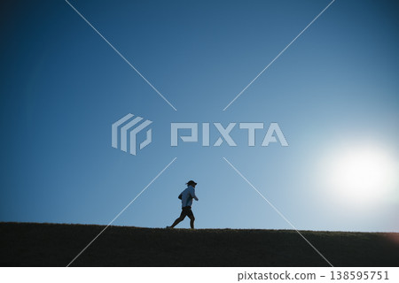 A person running along the embankment road against the twilight sky. 138595751