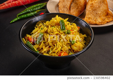 Vibrant Indian vegetable pilaf with fried samosas and raw vegetables on a dark tabletop Vibrant Indian vegetable pilaf with fried samosas and raw vegetables on a dark tabletop 138596402