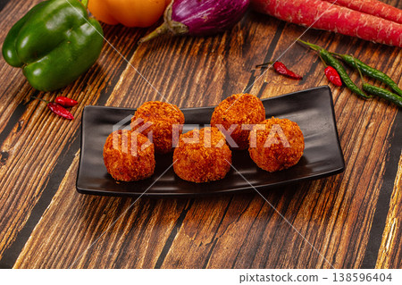 Golden fried cheese and vegetable balls, appetizer dish with fresh chili, peppers, and carrots on a wood table. 138596404