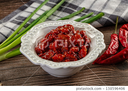 Spicy red chili pickle in a white bowl on a rustic wooden table with fresh ingredients 138596406