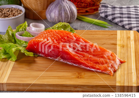 Fresh raw salmon fillet on a wooden board with garlic, onion, and spices 138596415