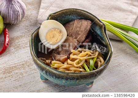Asian beef ramen soup with egg and noodles in a ceramic bowl with fresh ingredients. Asian beef ramen soup with egg and noodles in a ceramic bowl with fresh ingredients. 138596420